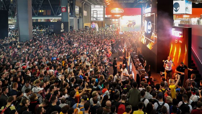 Public jeune et connecté au salon Paris Games Week découvrant des goodies personnalisés originaux sur un stand exposant